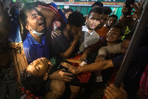 A policeman aims his weapon at protesters during a curfew imposed following violence during protests against Prime Minister Sheikh Hasina and her government, in Dhaka