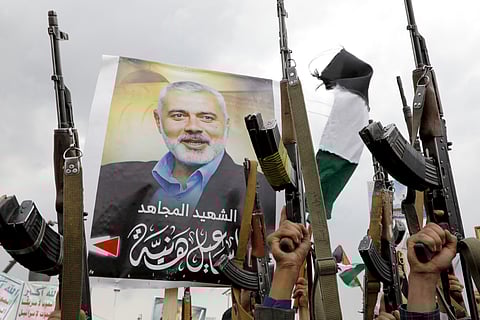 Yemeni protesters raise their machine guns during a protest to condemn the killing of Hamas leader Ismail Haniyeh, in Sanaa, Yemen, Friday, Aug. 2, 2024. Arabic reads, "Martyr Ismail Haniyeh". 
