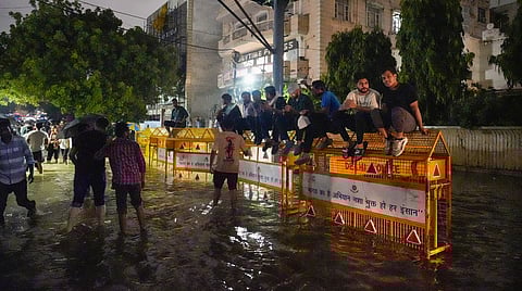 File - Students sit on barricades amid waterlogging in front of Rau's IAS Study Circle at Old Rajinder Nagar, in New Delhi, Wednesday, July 31