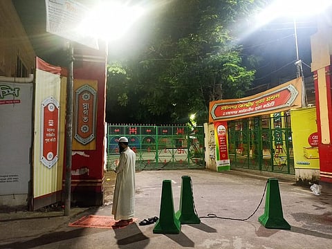 A Muslim man offering prayer while standing guard infront of the Dhakeshwari Temple in Bangladesh. 