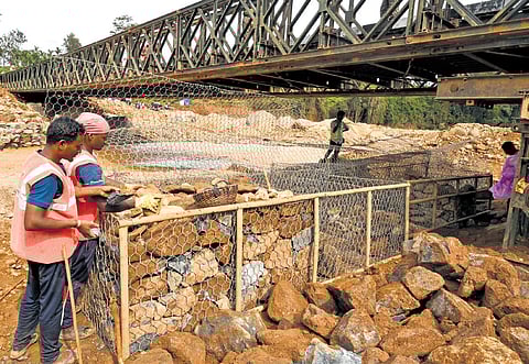 Workers constructing a gabion wall on Wednesday to reinforce the Bailey bridge built by the Army after the massive landslide in Wayanad 