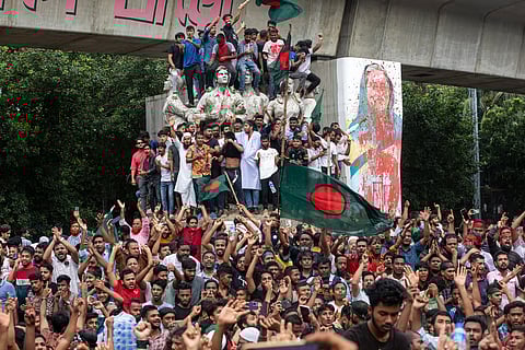 Protesters climb a public monument as they celebrate the news of Prime Minister Sheikh Hasina's resignation, in Dhaka, Bangladesh, Monday, Aug. 5, 2024.