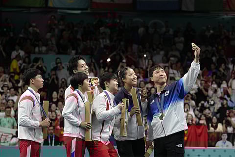  South Korea's Lim Jonghoon, right, takes a selfie with North Korea's Ri Jong Sik, left, and Kim Kum, second left, China's Wang Chuqin, background, and Sun Yingsha, center, and his teammate Shin Yubin, right, and Lim Jonghoon during the medal ceremony at the 2024 Summer Olympics, July 30, 2024, in Paris, France. 
