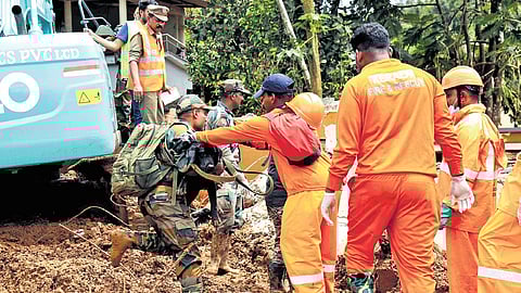 Fire and rescue services personnel help Army officers pass through the slush for search operation at Chooralmala 