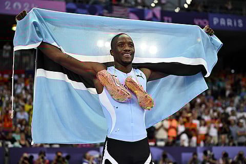 Gold medallist Botswana's Letsile Tebogo celebrates with the national flag after winning the men's 200m final of the athletics event at the Paris 2024 Olympic Games on August 8, 2024.