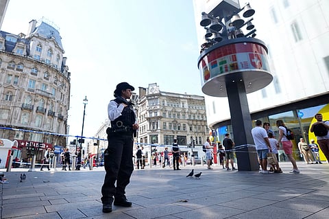 A Police officer stands at the scene in Leicester Square, as a man was arrested with the accusation of stabbing an 11-year-old girl and 34-year-old woman, in London, Monday Aug. 12, 2024. 