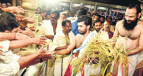 Thantri Kandararu Mahesh Mohanaru and Melsanthi P N Mahesh Namboothiri distribute paddy spikes to devotees in front of the Sreekovil at Sabarimala temple on Monday