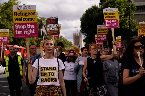 People hold placards as they march during an anti-far right protest in London, Saturday, Aug. 10, 2024.