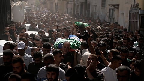 Mourners march during a funeral with the bodies of Palestinians.