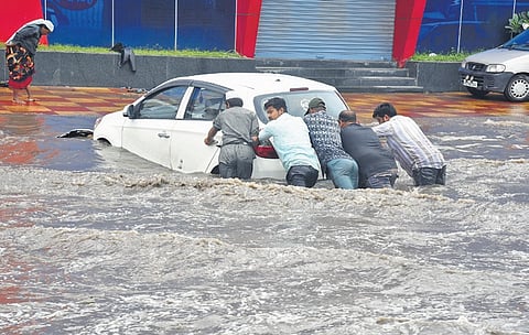 A car stuck on a flooded road being pushed by people in Hyderabad on Tuesday