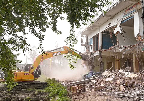 An excavator being used to demolish an illegal shopping complex owned by Moin Khan, an accused in a gang-rape case, in Ayodhya.