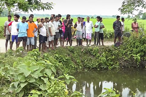 People gather near the pond where prime accused in the alleged rape of a minor girl jumped and died, at Dhing, in Nagaon district, Saturday, Aug. 24.
