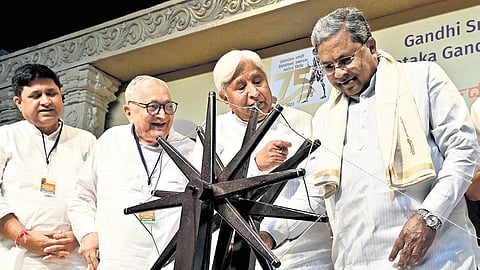 CM Siddaramaiah tries his hand at the charkha at a seminar on Mahatma Gandhi in Bengaluru