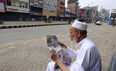 A man reads morning newspaper in a market, which closed due to strike called by traders to protest a rise in electricity costs and new taxes imposed on shop owners, in Peshawar, Pakistan, Wednesday, Aug 28, 2024.