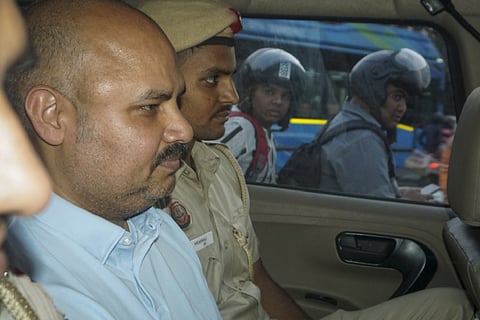 In this May 20, 2024 file photo, police personnel with Delhi Chief Minister Arvind Kejriwal's aide Bibhav Kumar leave Kejriwal's residence after recreation of the scene in MP Swati Maliwal's assault case, in New Delhi.