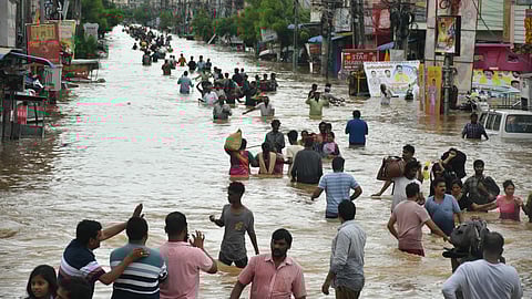 Residents of Singh Nagar wade through the flood after the Budameru canal breach in Vijayawada.