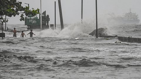 Youths wade in a storm surge along Manila Bay amid heavy rains brought by Tropical Storm Yagi in Manila on September 2, 2024.
