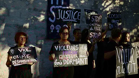 Demonstrators hold placards during a protest outside the courthouse during the trial of a man accused of drugging his wife for nearly ten years and inviting strangers to rape her at their home in Mazan.