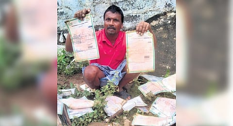 A flood victim shows the documents destroyed by floods in Khammam