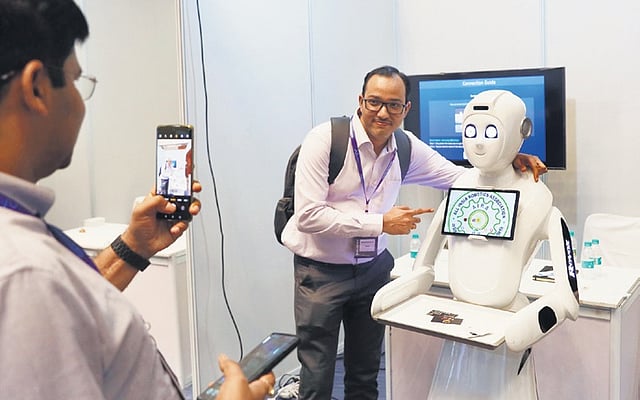 A man takes a photograph with a robot during the event at HICC in Hyderabad on Thursday