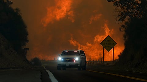 The Line Fire jumps highway 330 as an emergency vehicle is driven past Saturday, Sept. 7, 2024, near Running Springs, California.