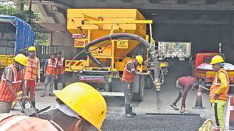 BBMP workers use a jet patcher machine, which was brought from Maharashtra, to fill potholes near Nayandahalli Junction on Wednesday 