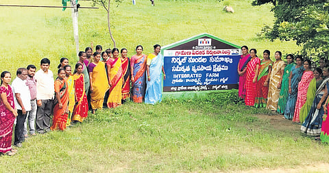 Members of the Nirmal Mandal Samaikya pose in front of the signboard outside the integrated farm in Nirmal district