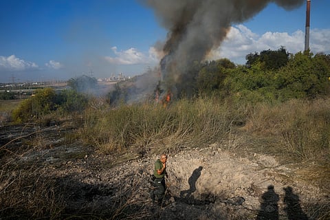 A police officer inspects the area around a fire after the military said it fired interceptors at a missile that landed in central Israel on Sunday.