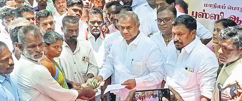 TVK general secretary Bussy Anand handing over assistance to a fisherman whose boat was damaged, in Nagapattinam on Sunday.