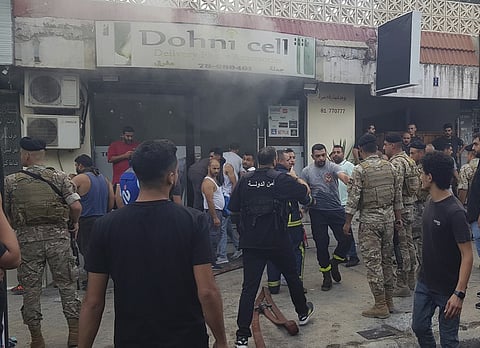 Lebanese soldiers and firefighters gather outside a mobile shop after what is believed to be the result of a walkie-talkie exploding inside it, in