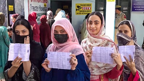 Women voters show their voting slips at a women-only polling station during the first phase of the Jammu and Kashmir Assembly elections in Kishtwar district.