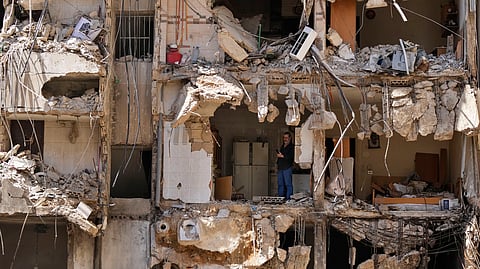 A man watches rescuers sift through the rubble as they search for people still missing at the site of Friday's Israeli strike in Beirut's southern suburbs, Monday, Sept. 23, 2024.