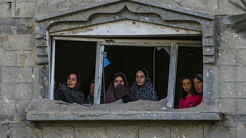 Palestinians look at the destruction after an Israeli airstrike on a crowded tent camp housing Palestinians displaced by the war in Muwasi, Gaza Strip