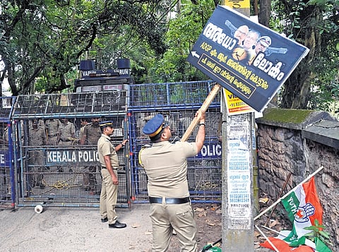 A police officer removes a flex board mocking ADGP Ajith Kumar, which was erected by Youth Congress workers at the construction site of the cop’s house, at Kowdiar in Thiruvananthapuram on Friday.