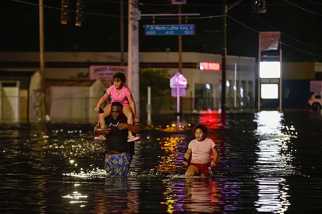 Jamir Lewis wades through floodwaters with his two daughters, Nylah and Aria, in the aftermath of Hurricane Helene, in Crystal River, Florida.