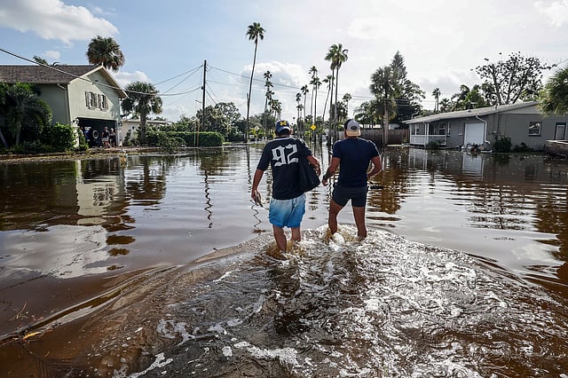 Thomas Chaves and Vinny Almeida walk through floodwaters from Hurricane Helene in an attempt to reach Chaves's mother's house in the Shore Acres neighborhood in St. Petersburg, Florida.