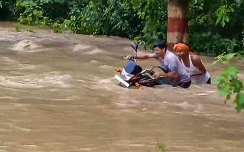 Commuters wade through a flooded area after an increase in the water level of Gandak river due to heavy rainfall, in Bagaha, Bihar, Saturday, Sept 28, 2024.