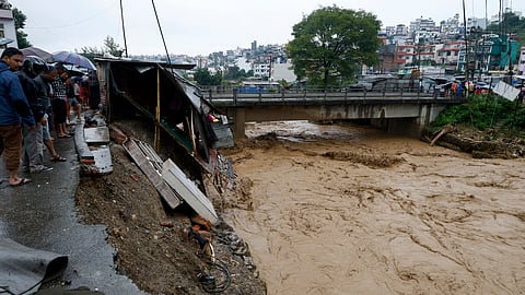 People gather at the edge of the Bagmati River in spate after heavy rains in Kathmandu, Nepal.