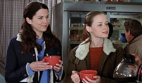 A still from 'Gilmore Girls' showing Lorelai and her daughter Rory with their cups of coffee