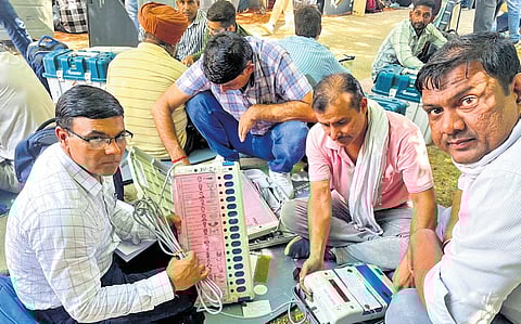 Officials check EVMs and VVPATs before leaving for their respective polling stations on the eve of the Haryana Assembly elections.