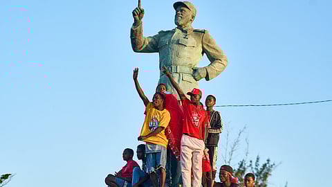 Supporters of Mozambique Liberation Front (FRELIMO) party climb on a statue of former President of Mozambique Samora Machel attend a rally on in Beira on October 6, 2024. 