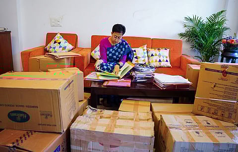 Delhi Chief Minister Atishi signing files surrounded by packed cartons of her belongings, at her Kalkaji residence in New Delhi on Thursday. 
