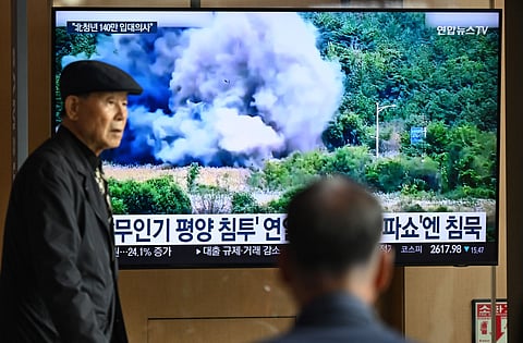A man walks past a television screen showing a news broadcast with footage of an explosion on a road connecting North and South Korea on October 15, 2024, at a train station in Seoul on October 16, 2024. 