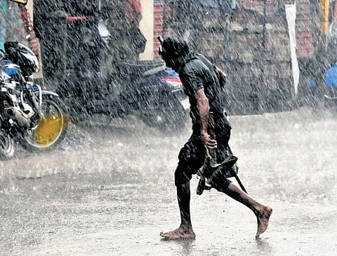 A man runs to find shelter amid heavy rains in Karimnagar on Thursday | Express