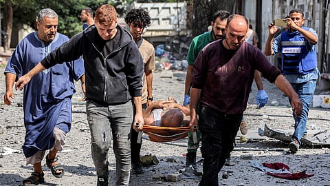 People carry on a gurney a man extricated from the rubble of a collapsed building following Israeli bombardment after his rescue in the Saftawi district in Jabalia in the northern Gaza Strip on October 15, 2024.