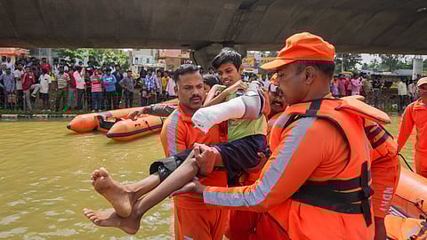 NDRF personnel carry a boy with a plaster cast on his arm as they conduct rescue operations after floodwater entered the Kendriya Vihar apartment following heavy rain, in Bengaluru.