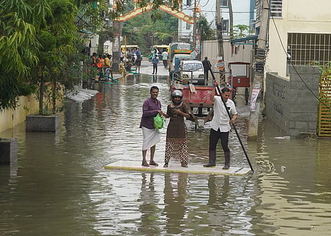 Residents use a discarded door to cross a flooded street in Bengaluru’s Horamavu