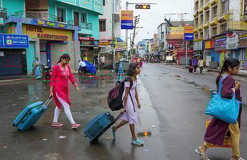 People with their luggage leave coastal areas ahead of the landfall of Cyclone 'Dana'