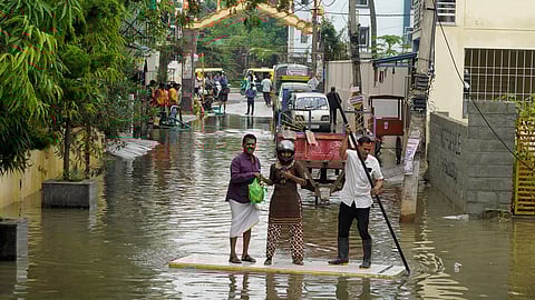 Residents use a discarded door to cross a flooded street in Bengaluru’s Horamavu on Thursday. 