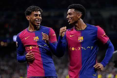 Barcelona's Lamine Yamal, left, celebrates with Barcelona's Alejandro Balde after scoring his side's third goal during a Spanish La Liga soccer match between Real Madrid and Barcelona at the Santiago Bernabeu stadium in Madrid, Spain, Saturday, Oct. 26, 2024.
